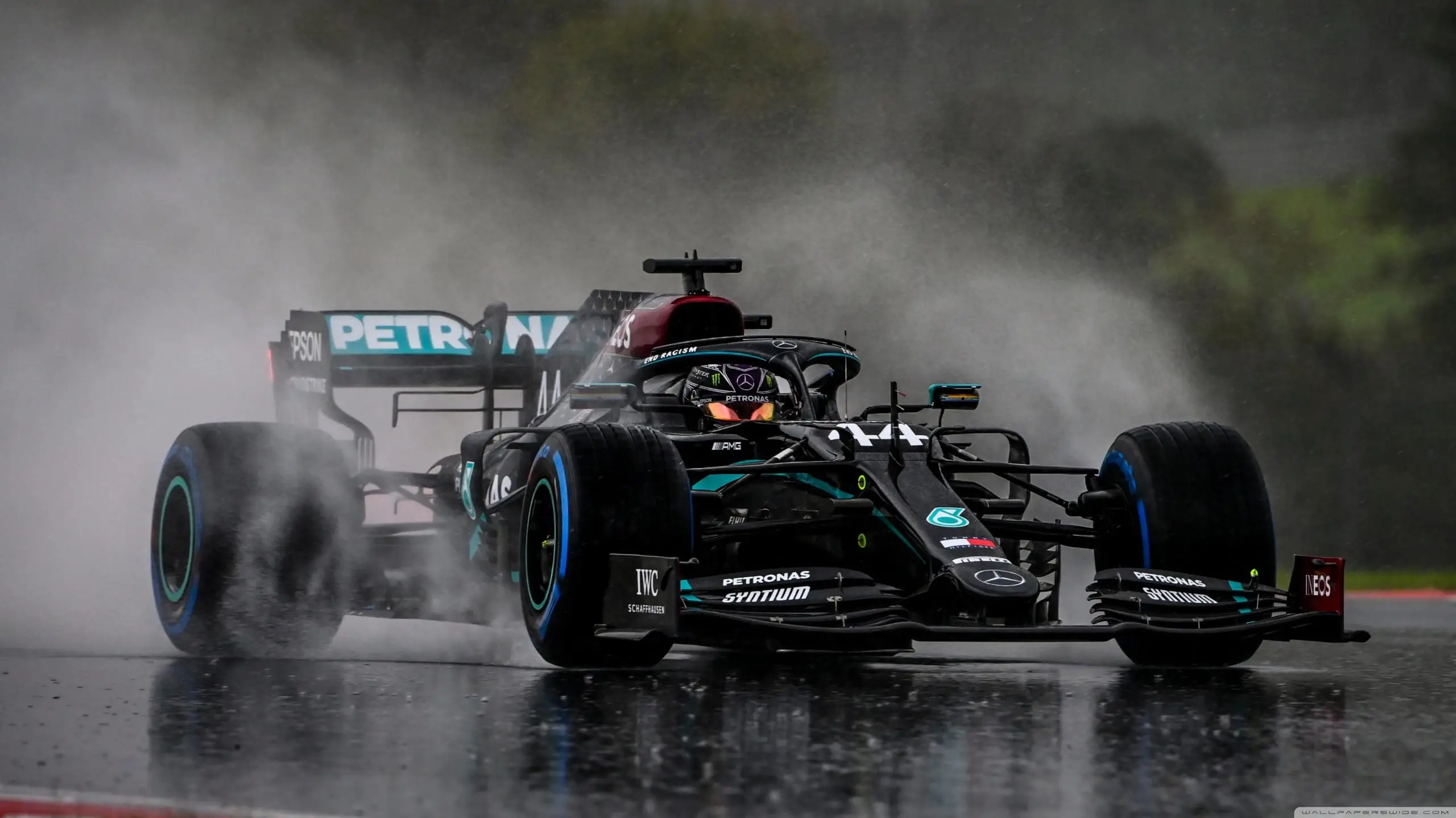 Formula 1 car throwing spray on a wet track